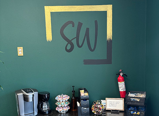 Styleworks Logo painted on a wall near a counter full of coffees and treats